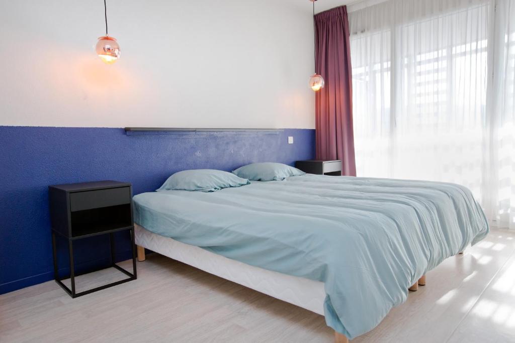 um quarto com uma cama grande e uma parede azul em Grand studio avec climatisation, balcon proche gare centre ville em Lourdes