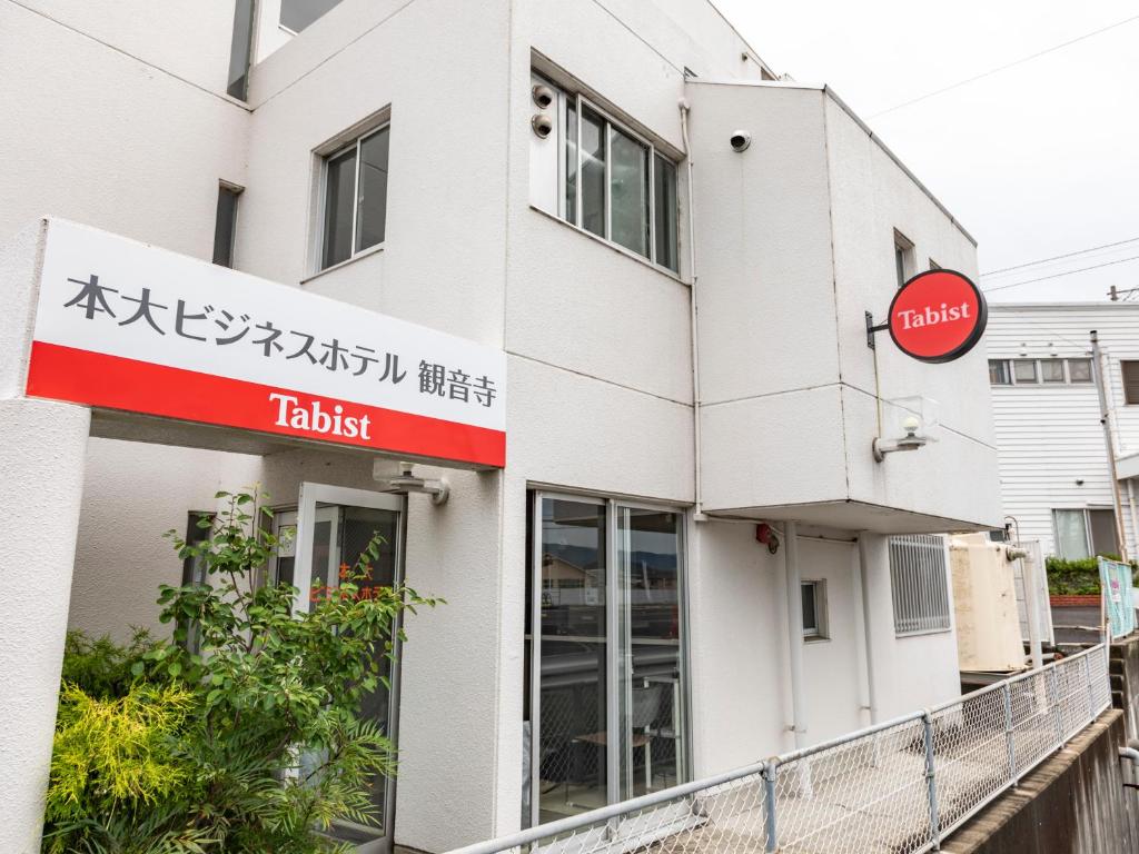 ein Gebäude mit einem Schild für ein Sushi-Restaurant in der Unterkunft Tabist Motodai Business Hotel Kanonji in Kanonji