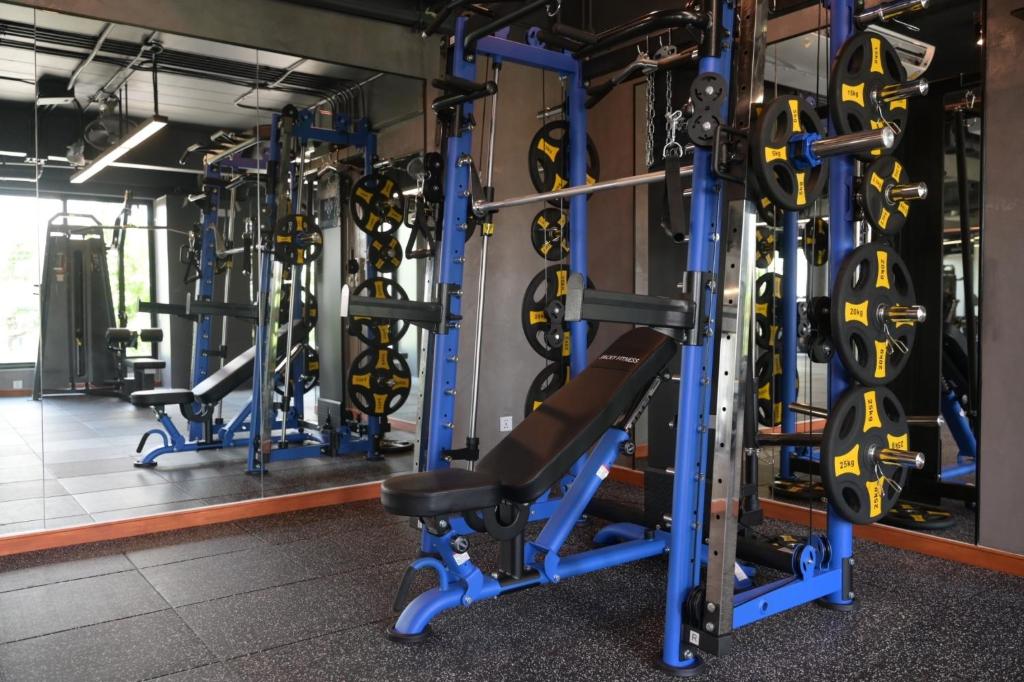 A strength-training area centers on a blue power rack with weight plates and a bench.