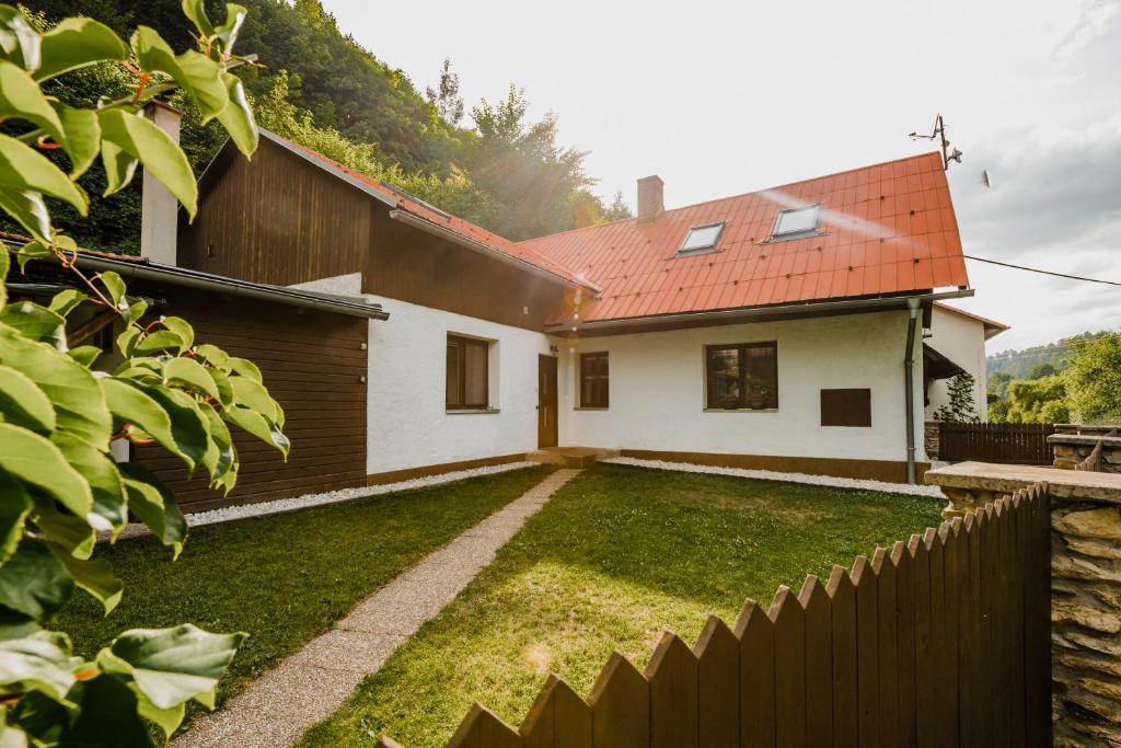 a white house with a red roof and a yard at Na Želivce chalupa Marie in Želiv