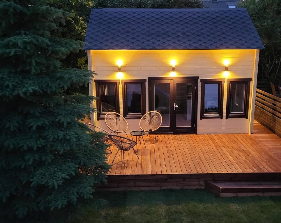 une maison avec deux chaises et des lumières sur une terrasse dans l'établissement Tiny house near Viljandi lake, à Viljandi