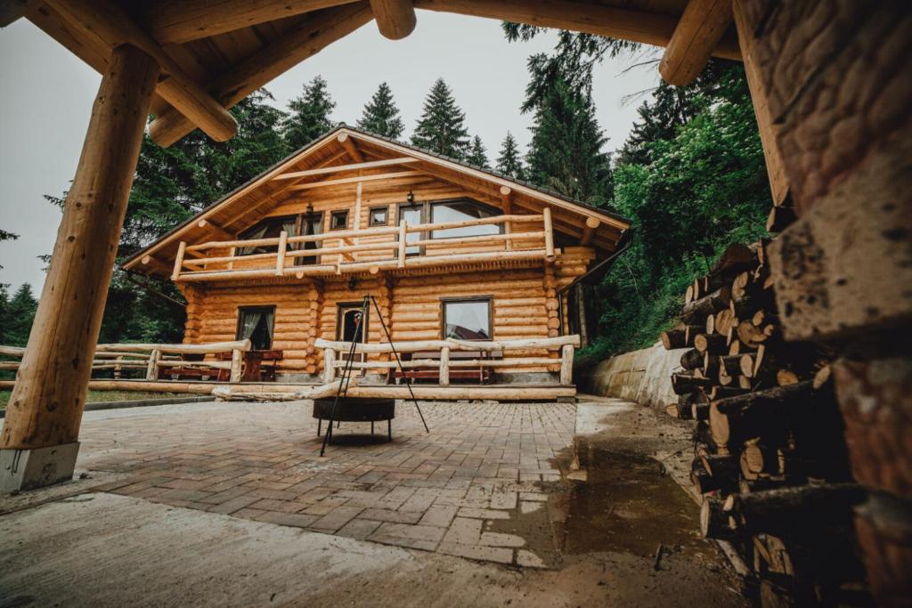 a log cabin in the woods with a porch at Q Chalet in Săcele