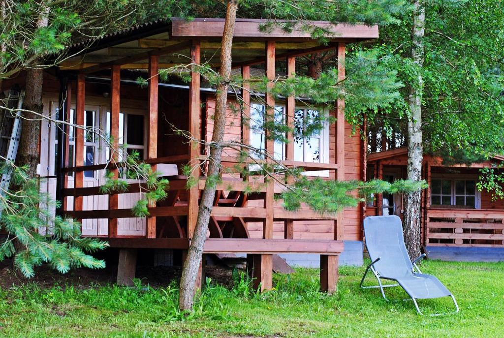 a wooden cabin with a bench in front of it at Laumių Nameliai in Anykščiai