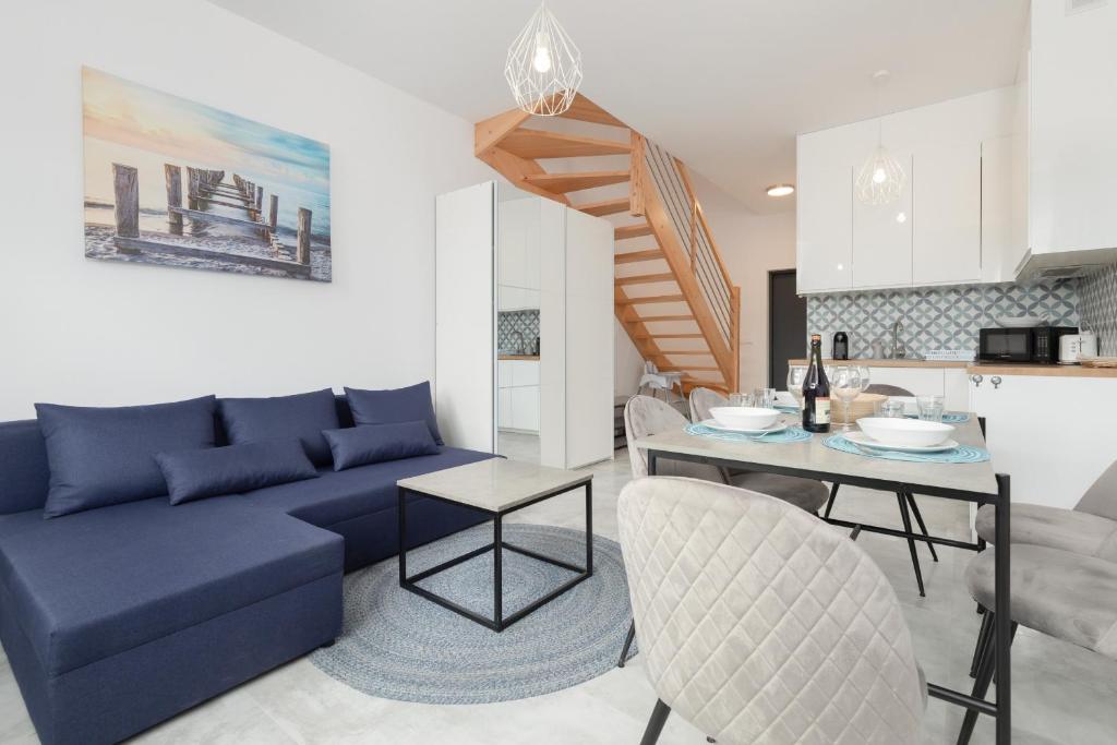 a living room with a blue couch and a table at Lake House Sosnowy Las Mielno by Renters in Mielno