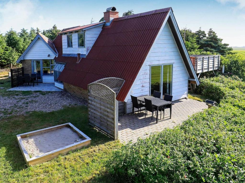a small white house with a patio and a table at 7 person holiday home in Lemvig in Trans