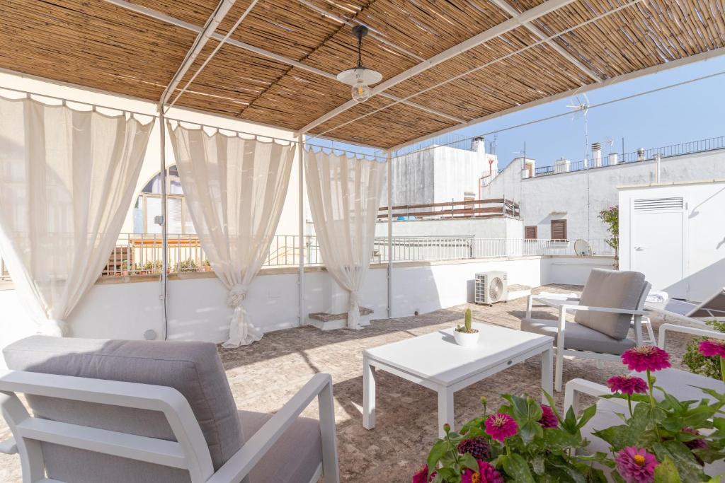eine Terrasse mit weißen Stühlen, einem Tisch und einigen Blumen in der Unterkunft Casa Vacanze L'angolo di Giadia in Matino