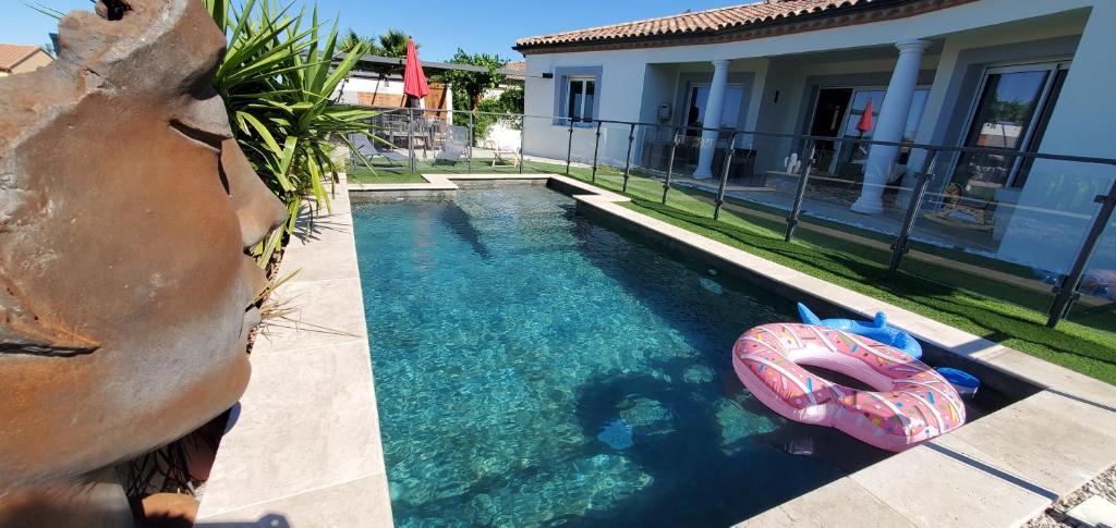 une piscine extérieure avec un radeau gonflable en face d'une maison dans l'établissement La Cersoise, 10 min des plages, à Cers