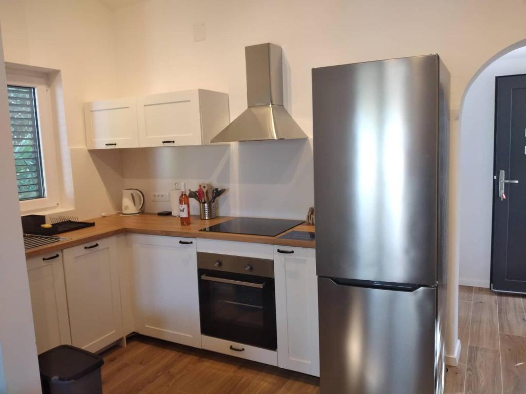 a kitchen with a stainless steel refrigerator and white cabinets at Apartmani LUNI in Premantura
