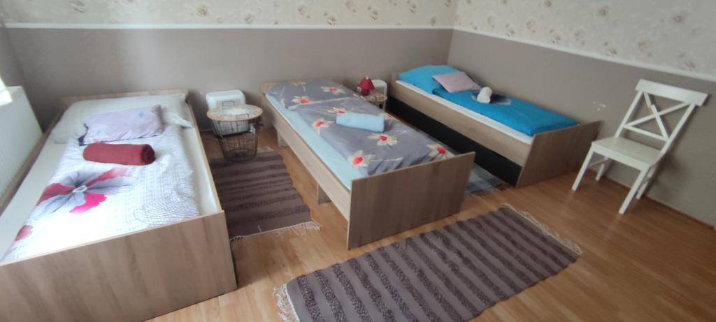a small room with two beds and a chair at Orsi Apartman / vendegház in Kecskemét