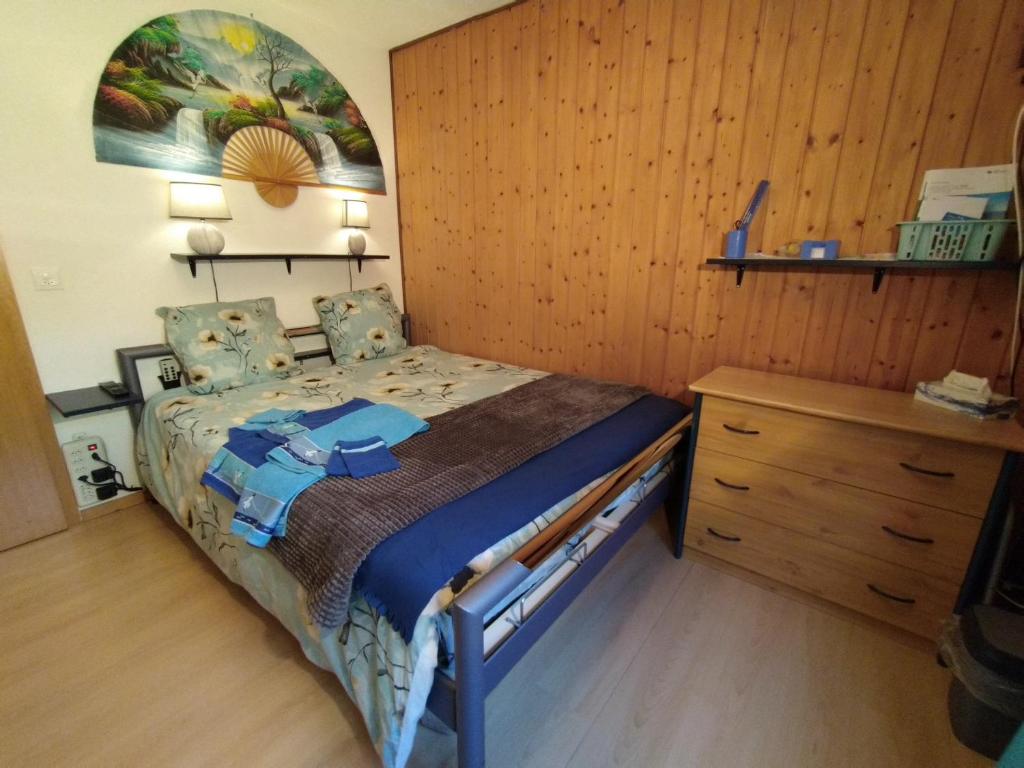 1 dormitorio con 1 cama y pared de madera en Chez l'Eveline en Les Bois