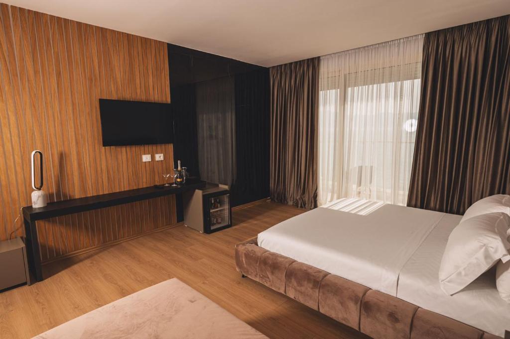 pokój hotelowy z łóżkiem i telewizorem w obiekcie Grand Mirage we Wlorze