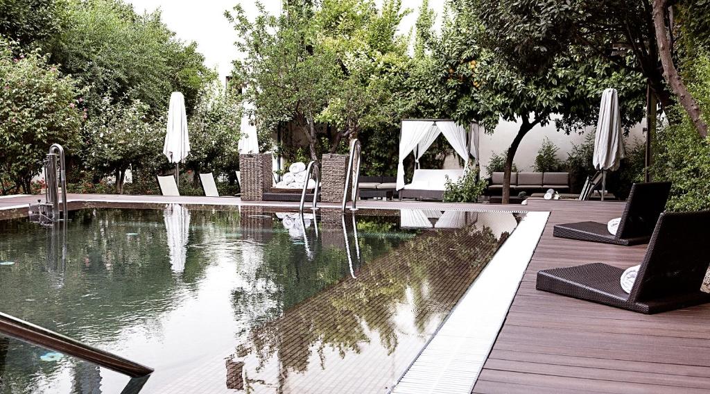 コルドバにあるHospes Palacio del Bailio, a Member of Design Hotelsのプールサイドのテーブルと椅子付きのスイミングプール