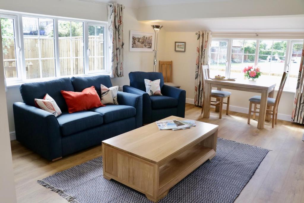 a living room with a blue couch and a table at Lawnside 3 in Budleigh Salterton