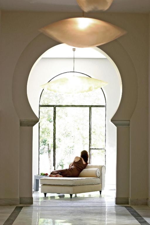 a person sitting on a couch in front of a window at Hospes Palacio del Bailio, a Member of Design Hotels in Córdoba