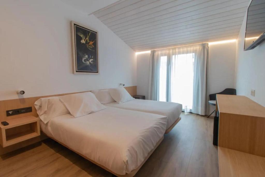a bedroom with a large white bed and a desk at Hotel Cortabitarte in Soria