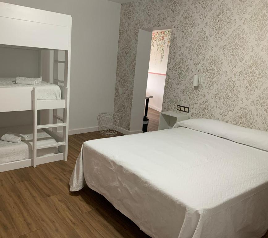 1 dormitorio con cama blanca y espejo en Hostal Solymar, en Louro