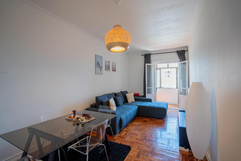 uma sala de estar com um sofá azul e uma mesa em The Av. Roma Apartment em Lisboa