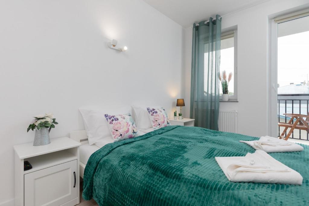 a white bedroom with a green bed with towels on it at Morska Apartment Dziwnówek by Renters in Dziwnówek