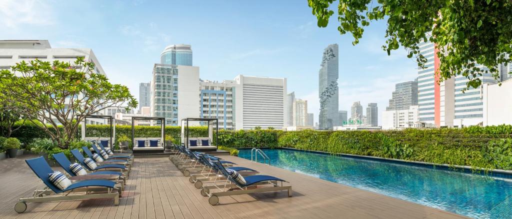 een rij ligstoelen naast een zwembad bij Le Meridien Bangkok in Bangkok