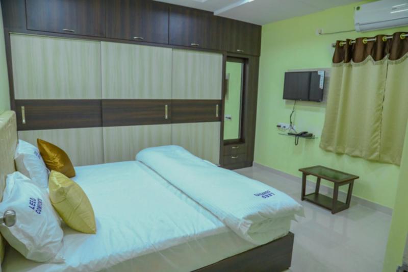 1 dormitorio con 1 cama grande y TV en Leeo Comforts en Visakhapatnam