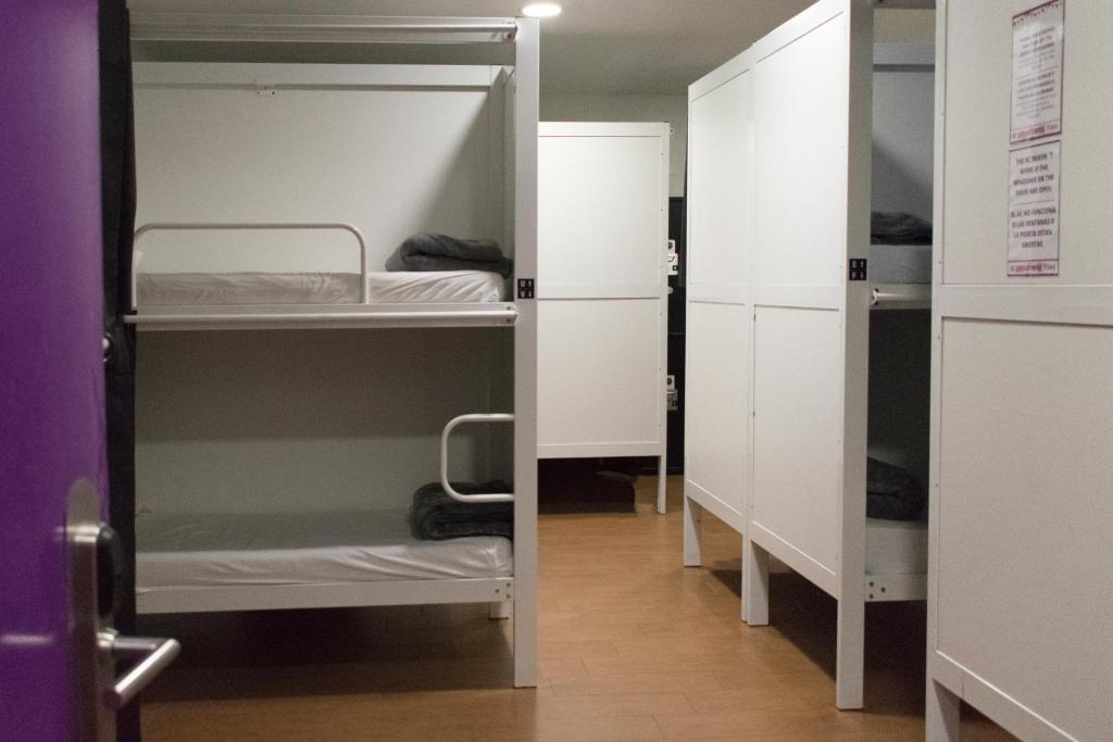a small room with two bunk beds and a door at Kabul Party Hostel Barcelona in Barcelona