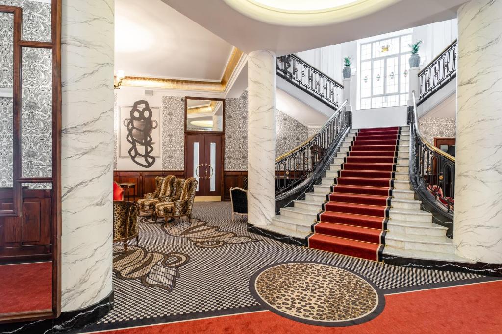 eine Treppe in einem Gebäude mit roten Teppichen und einer Lobby in der Unterkunft Hotel H15 Francuski Old Town in Krakau