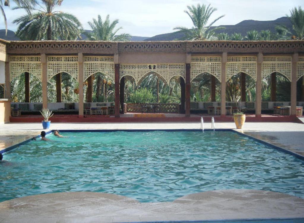 Tamnougalt的住宿－Kasbah Itrane，棕榈树建筑中的游泳池