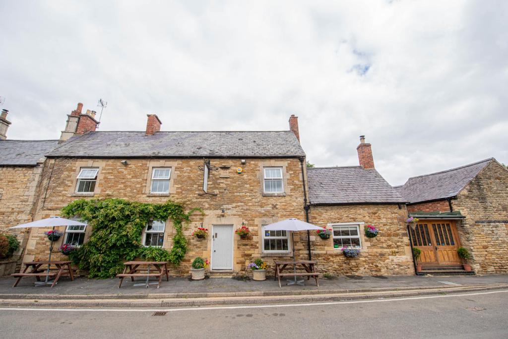 ein altes Backsteingebäude mit Tischen und Sonnenschirmen in der Unterkunft The George & Dragon Country Inn in Seaton