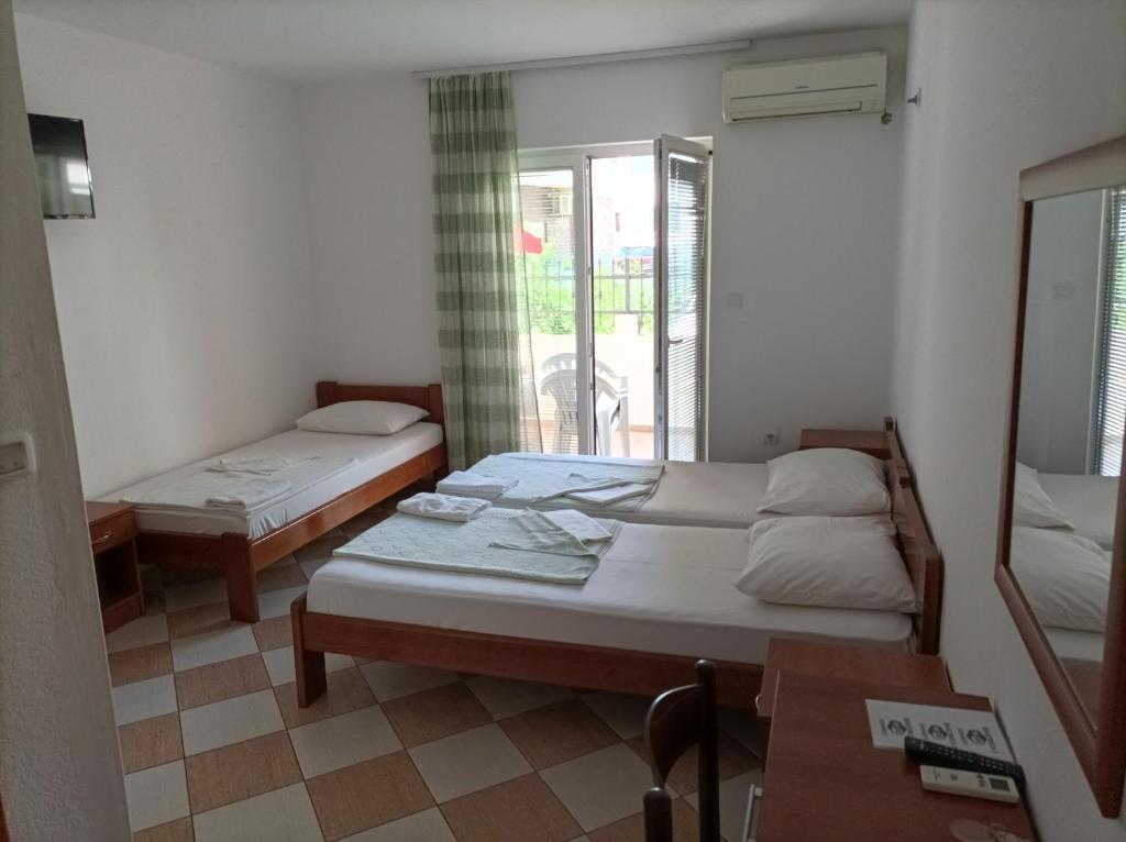 a room with two beds and a table and a window at Apartmani Baštrica in Budva