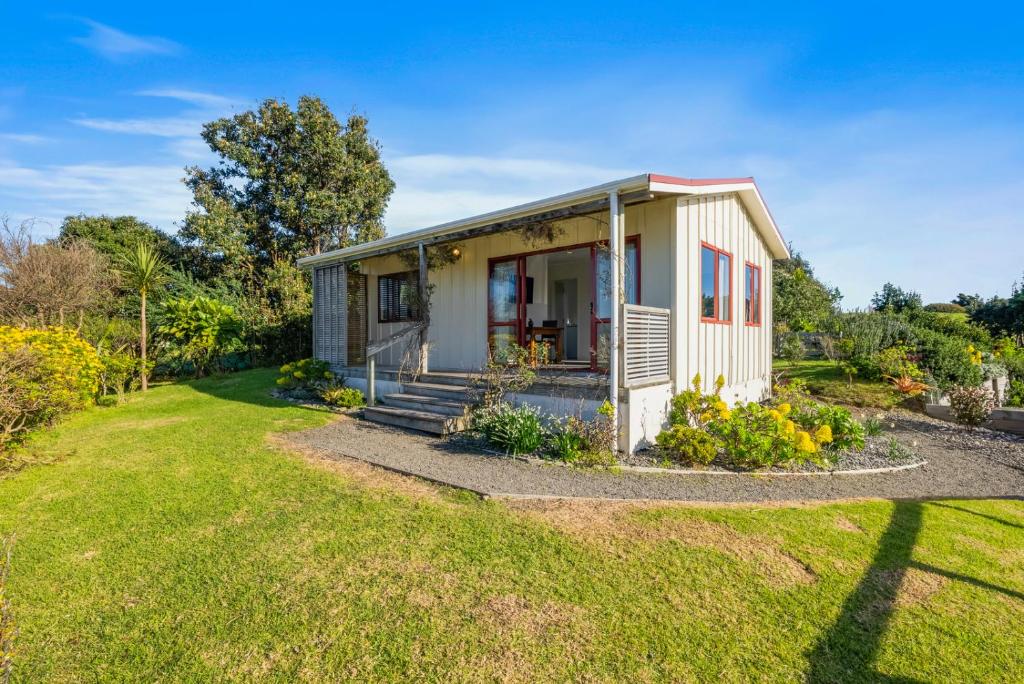 a tiny house in a garden with a yard at Cottage on Rutherford - Waikanae Holiday Home in Waikanae