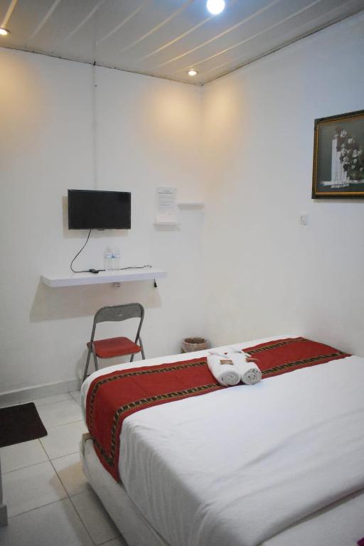 a bedroom with a bed and a tv on a wall at Homestay Legundi Syariah in Tanjungkarang