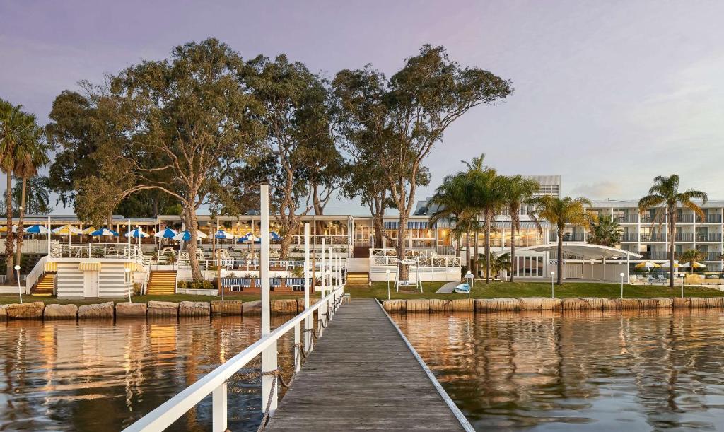 a dock in a marina with a hotel in the background at The Beachcomber Hotel & Resort, Ascend Hotel Collection in Toukley