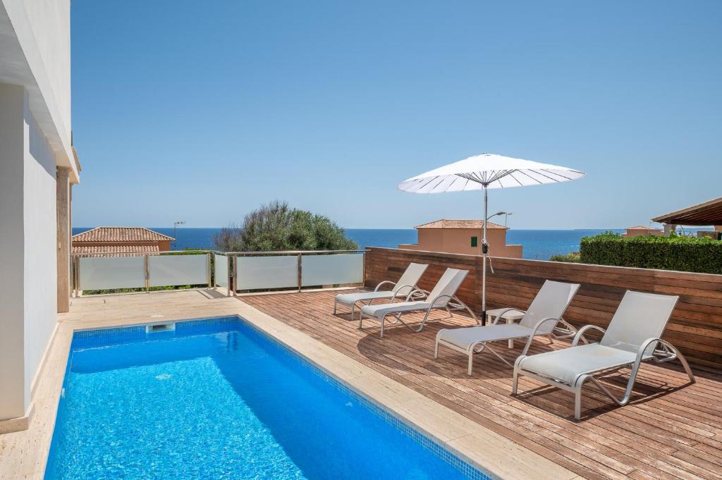 a pool with chairs and an umbrella next to a house at Villa Ullastre in Manacor