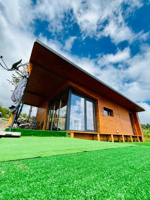 a house with a green lawn in front of it at Sweet Escape Vlădeasa in Rogojel