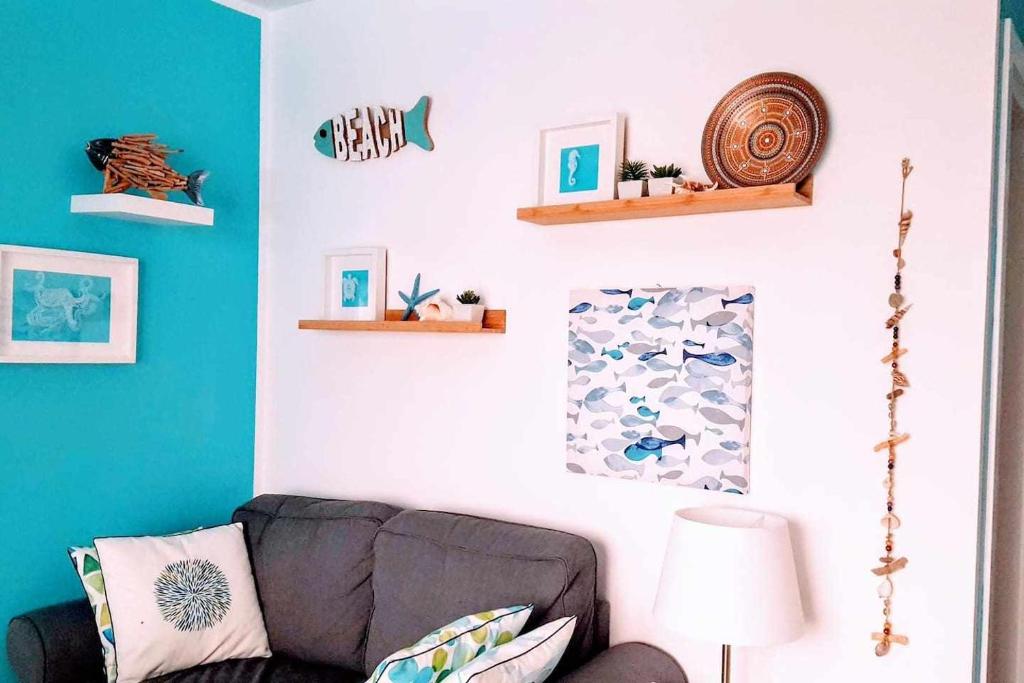 uma sala de estar com um sofá e paredes azuis em CorralejoDunas piscinas wifi tenis bicicletas em Corralejo
