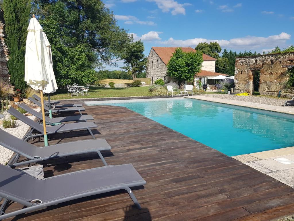 une piscine avec des chaises longues et un parasol dans l'établissement Le clos du Mûrier, à Fongrave