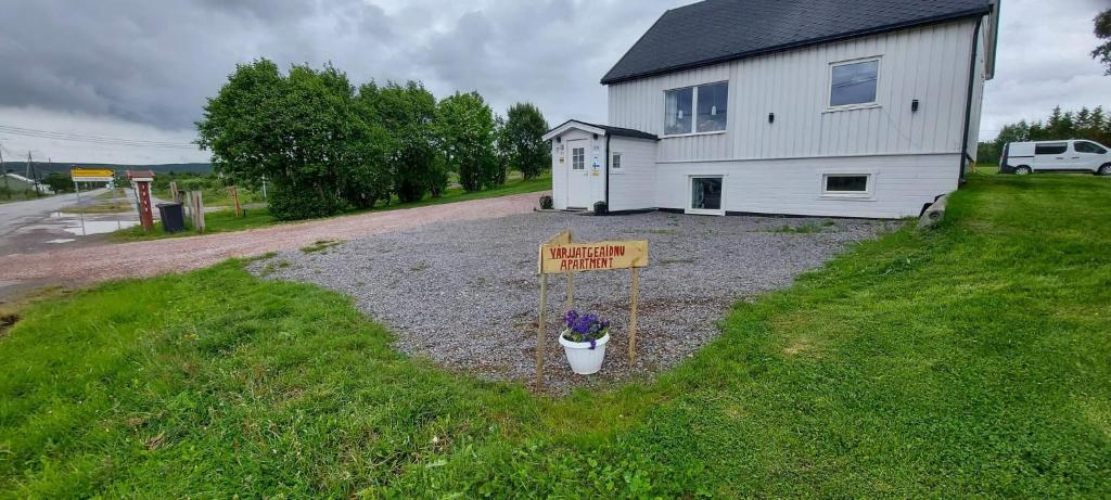 a house with a sign in front of a yard at Varjjatgeainu Apartment Nesseby in Varangerbotn