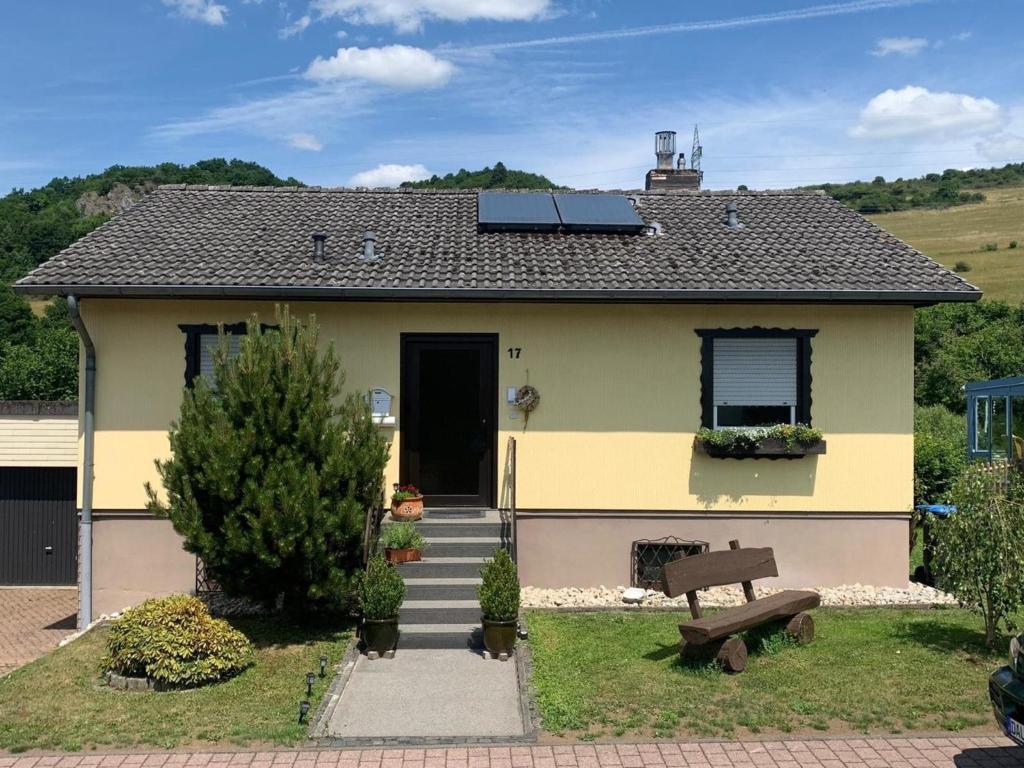 una casa amarilla con un banco delante en Ferienhaus Schwalbennest, en Gerolstein