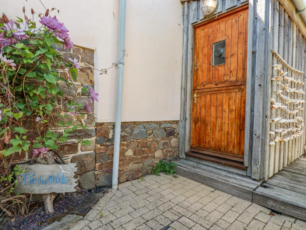 a wooden door on a building with a plant at Periwinkle in Bude