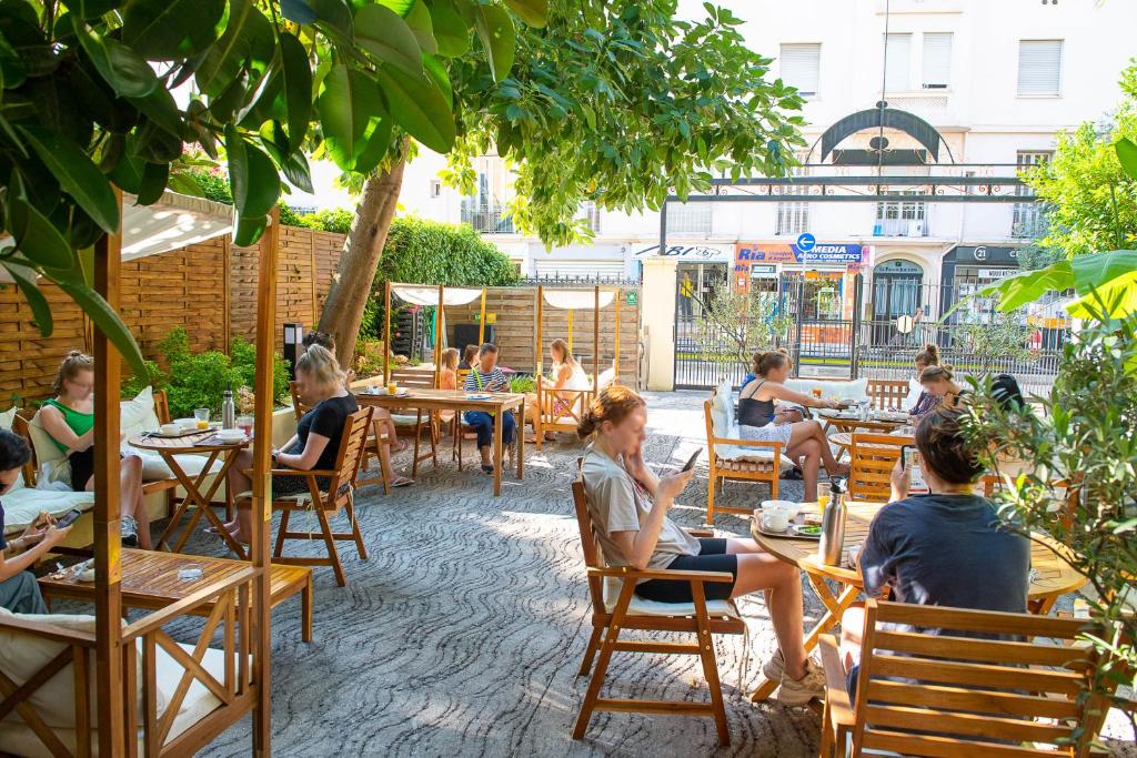 um grupo de pessoas sentadas em mesas em um pátio em Auberge de Jeunesse HI Nice Les Camélias em Nice