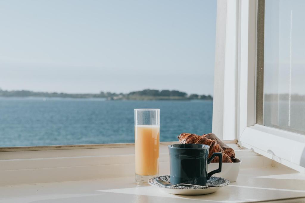 a glass of orange juice and a cup of coffee on a window at Hôtel Aux Tamaris - Vue Mer in Roscoff