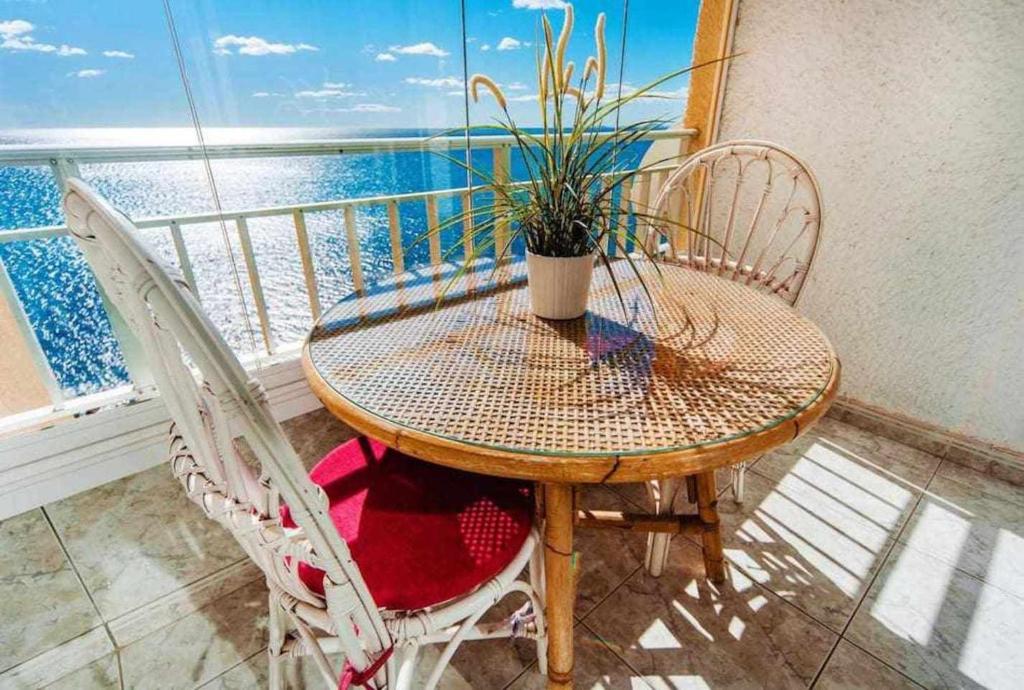 トレビエハにあるEspanhouse Maestro sea view apartmentのテーブル、椅子、鉢植えの植物が備わるバルコニー