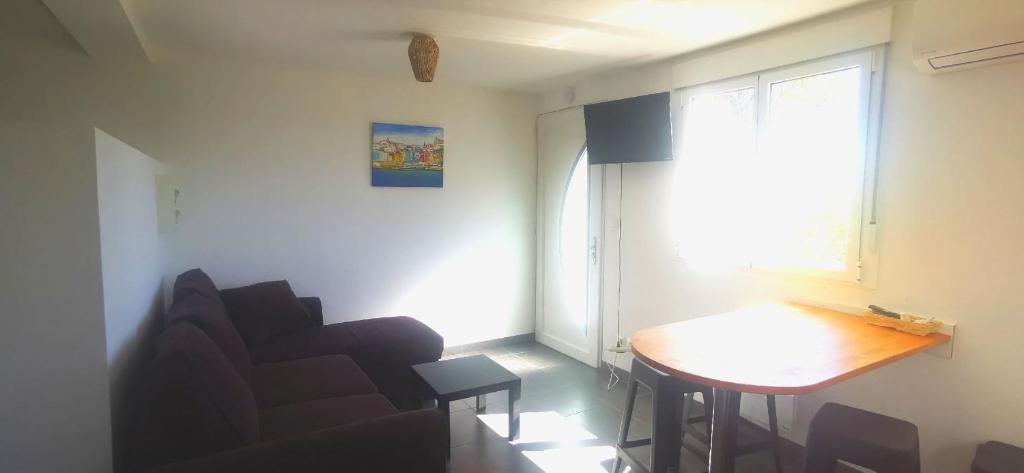 een woonkamer met een stoel, een tafel en een raam bij Spacieux studio Perols in Pérols