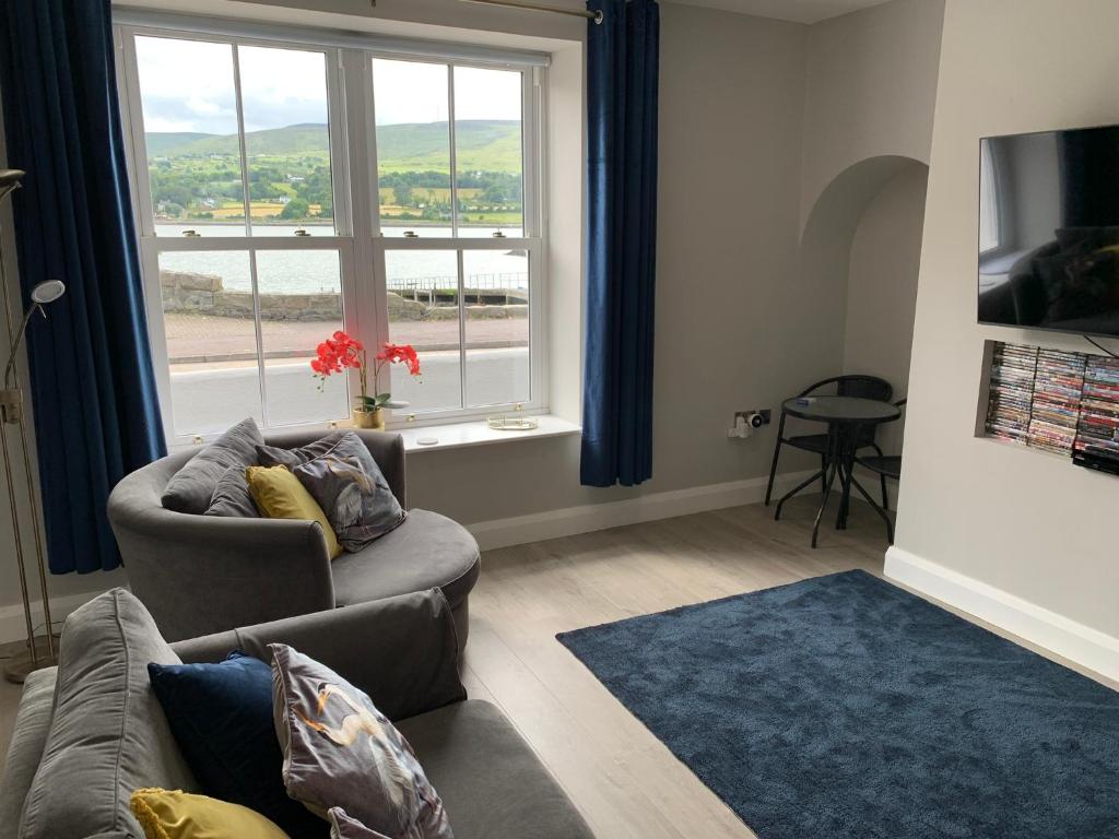 a living room with a couch and a large window at Seaview Aurora House - Central Luxury Apartment in Warrenpoint