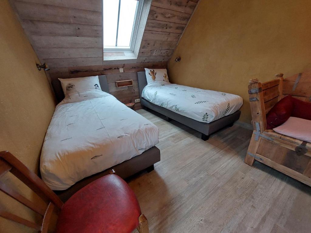 a small bedroom with two beds and a chair at B&B Clogher Farm in Poperinge