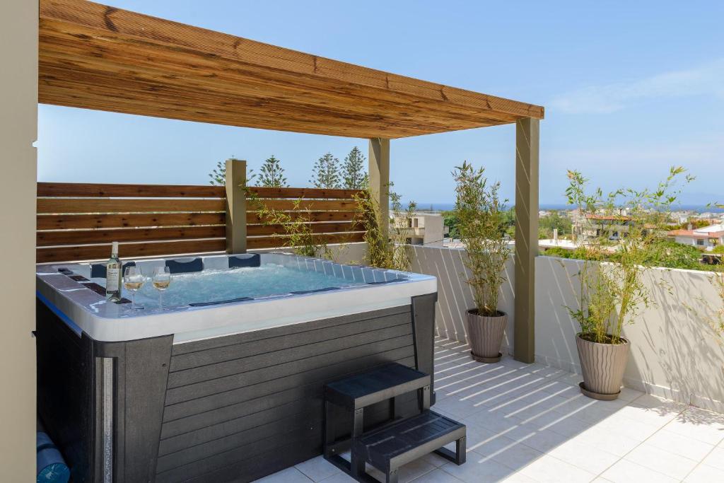 a hot tub on a patio with a wooden pergola at Atlas Villa in Kremasti