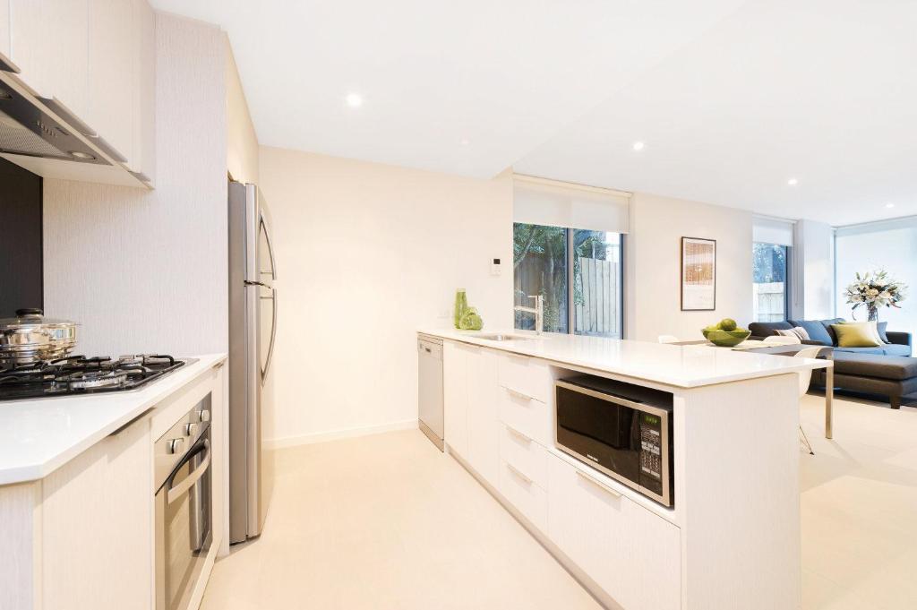 a kitchen with white appliances and a living room at Best Western Plus The Tudor Box Hill in Box Hill