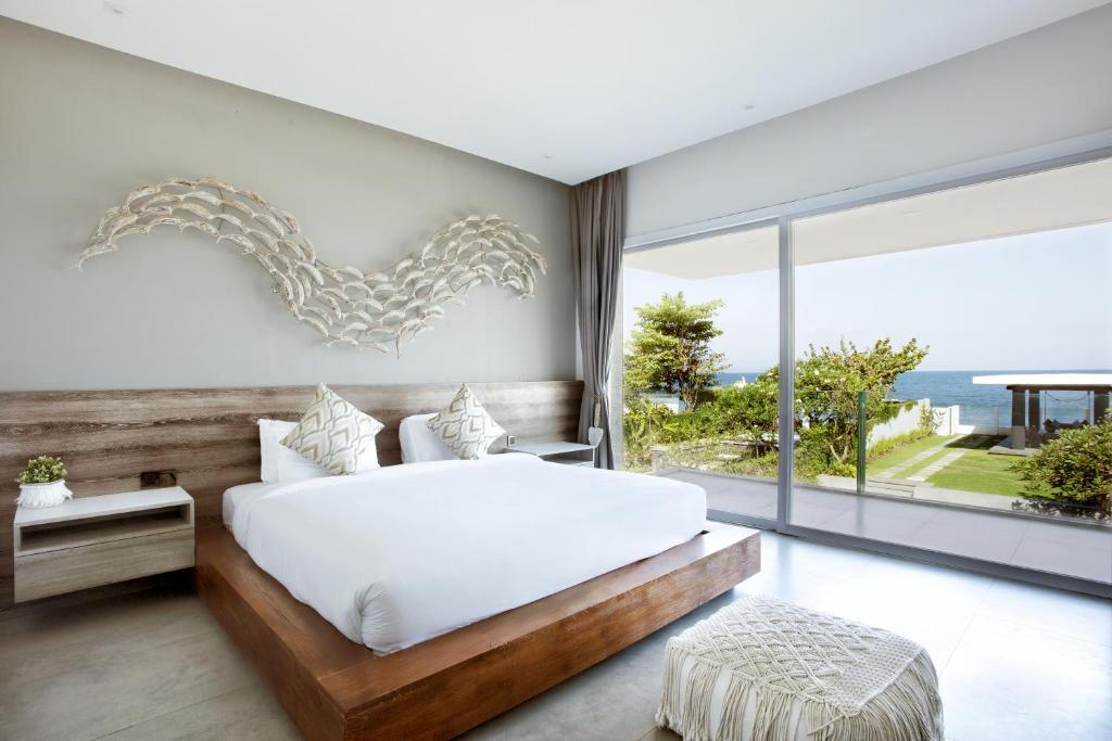 a bedroom with a white bed and a large window at Bali Diamond Estates & Villas in Keramas