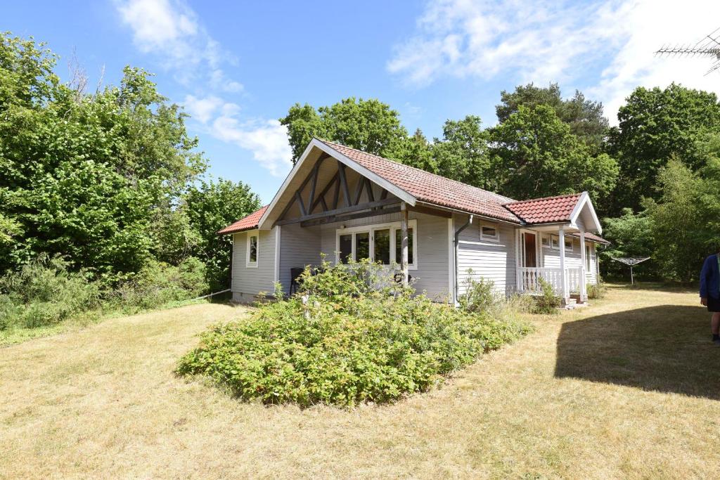 una pequeña casa blanca en un campo con árboles en Nice cottage on Öland by the sea, en Byxelkrok