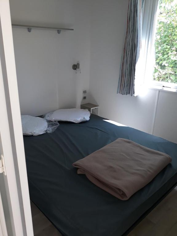 a bedroom with a bed with blue sheets and a window at Mobilhome 6 pers avec Clim in Saint-Georges-de-Didonne